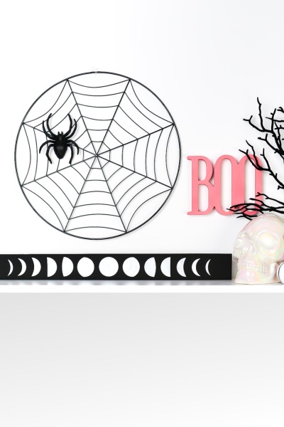 Moon artwork styled on a shelf with pink and black Halloween decor