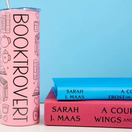 "Booktrovert" tumbler with a stack of books
